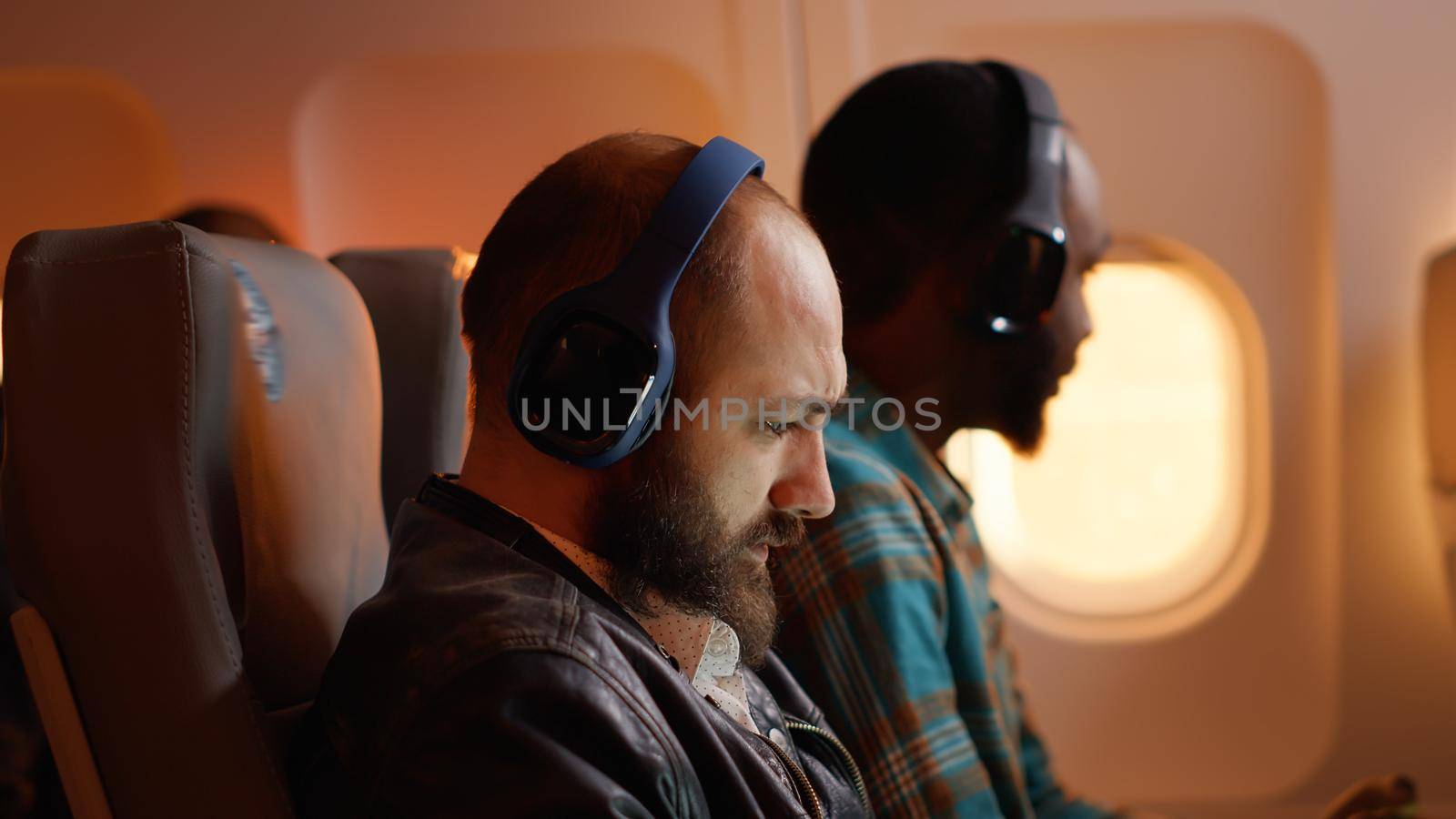 Passenger in airplane seat using laptop to work on flight by DCStudio