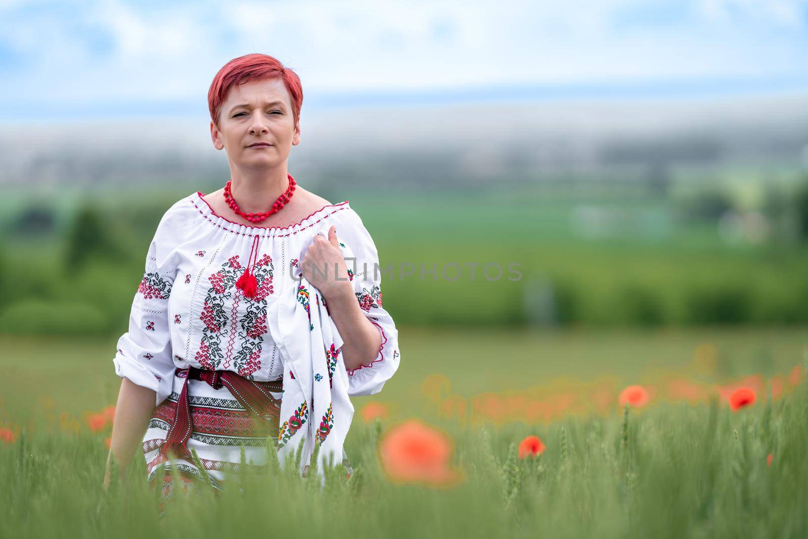 woman in Ukrainian national dress on a flowering poppy field.