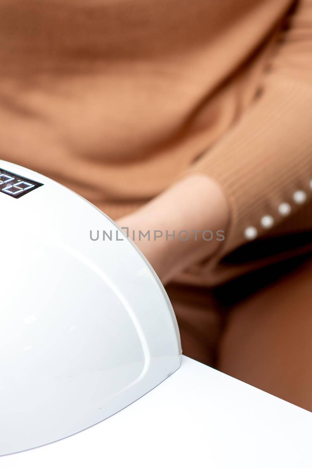 UV lamp gel polish manicure machine during process for drying of nails in beauty salon