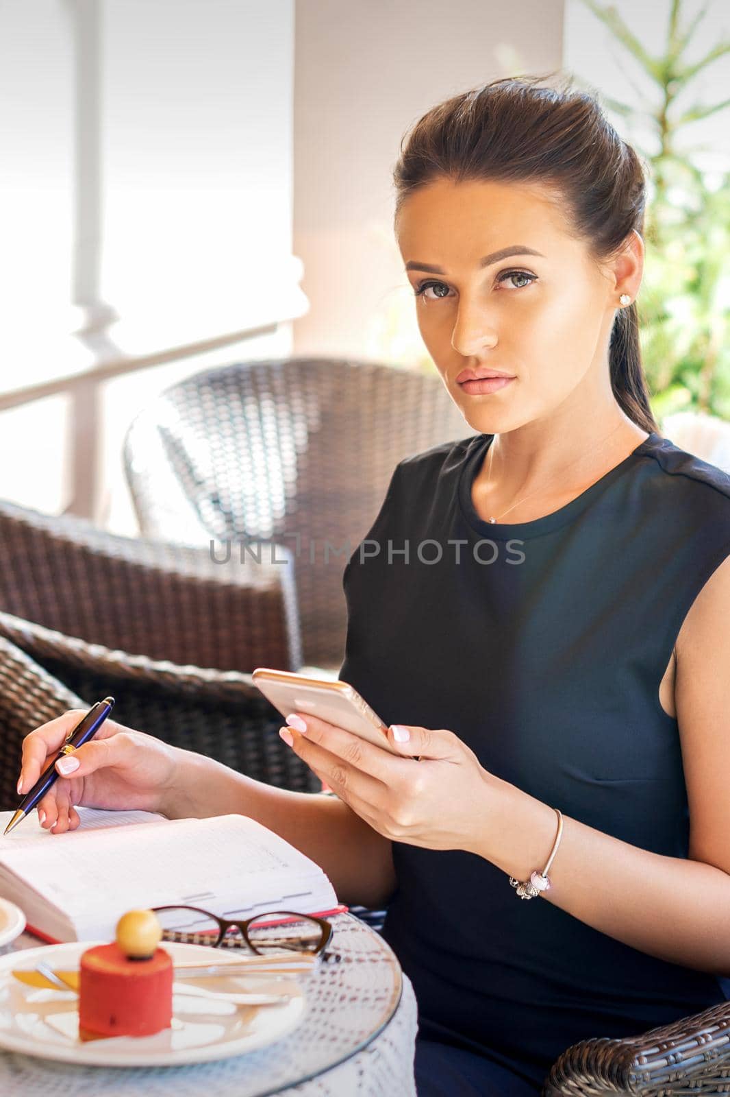 Portrait of beautiful young caucasian businesswoman with cell phone sitting in the cafe