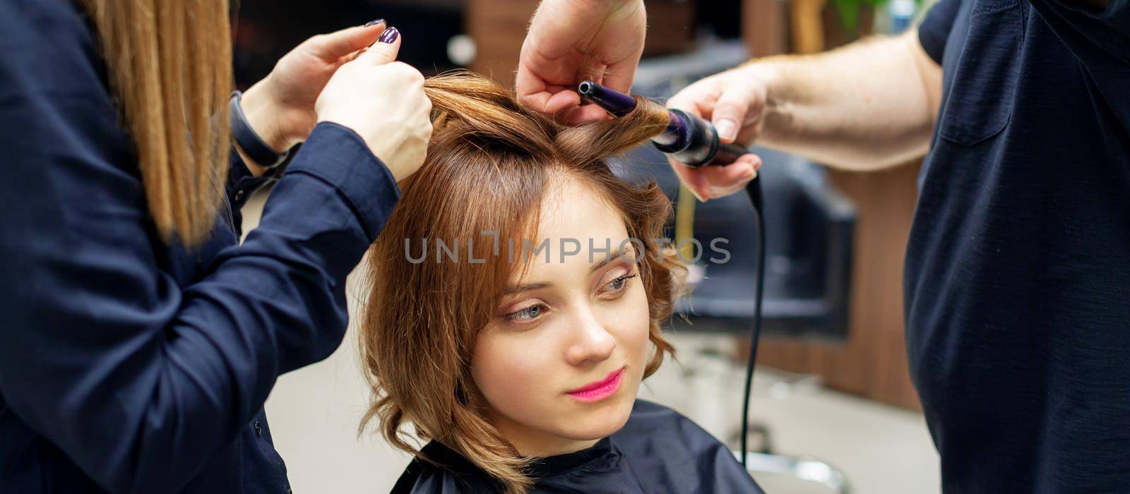 Hairdresser curling long light brown hair by okskukuruza