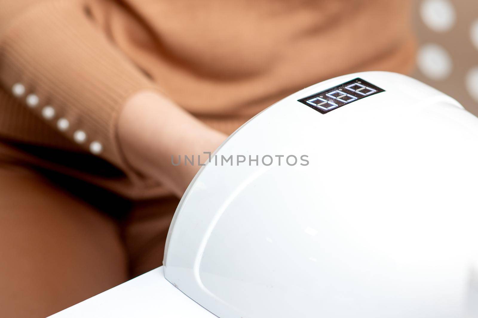 UV lamp gel polish manicure machine during process for drying of nails in beauty salon