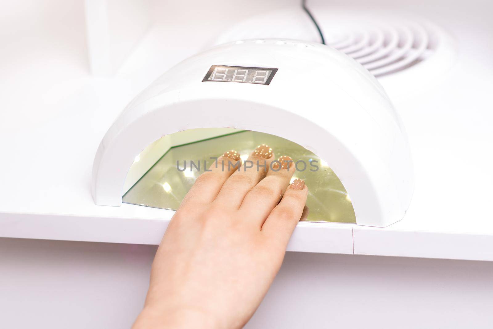 UV lamp gel polish manicure machine during process for drying of nails in beauty salon