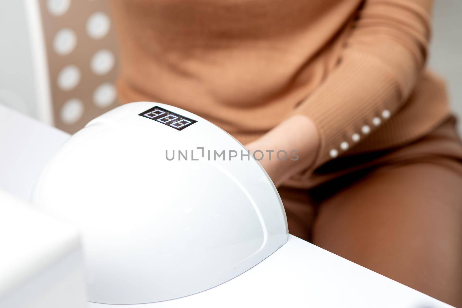 UV lamp gel polish manicure machine during process for drying of nails in beauty salon