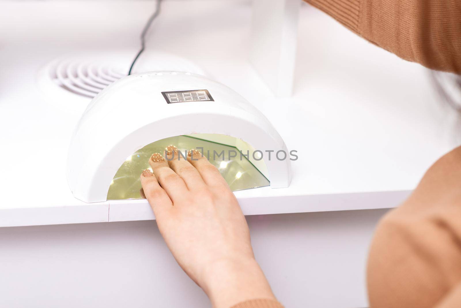UV lamp gel polish manicure machine during process for drying of nails in beauty salon