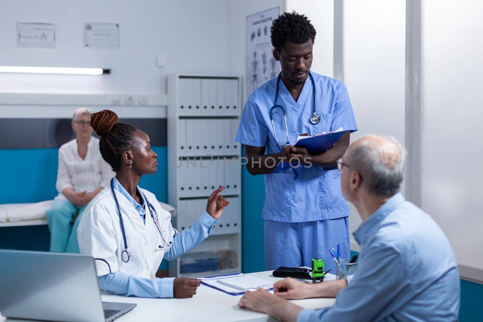 African american healthcare hospital staff reviewing senior patient record file while talking about treatment schedule. Clinic expert discussing with nurse about consultation appointments