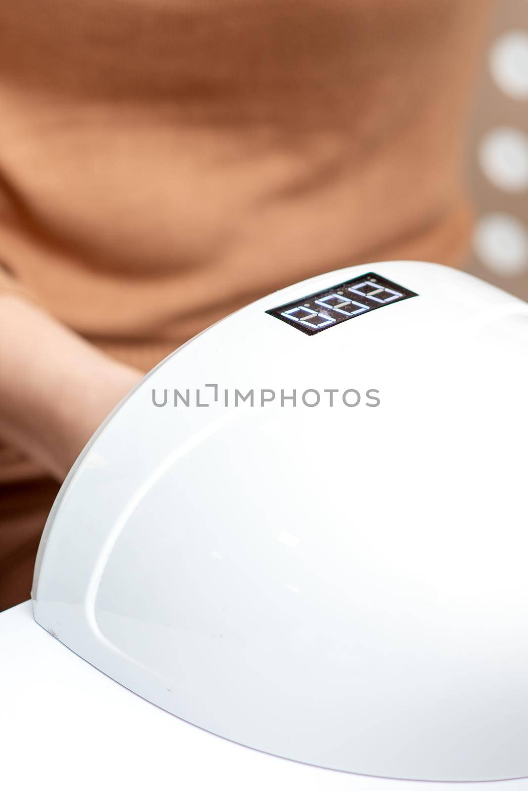 UV lamp gel polish manicure machine during process for drying of nails in beauty salon