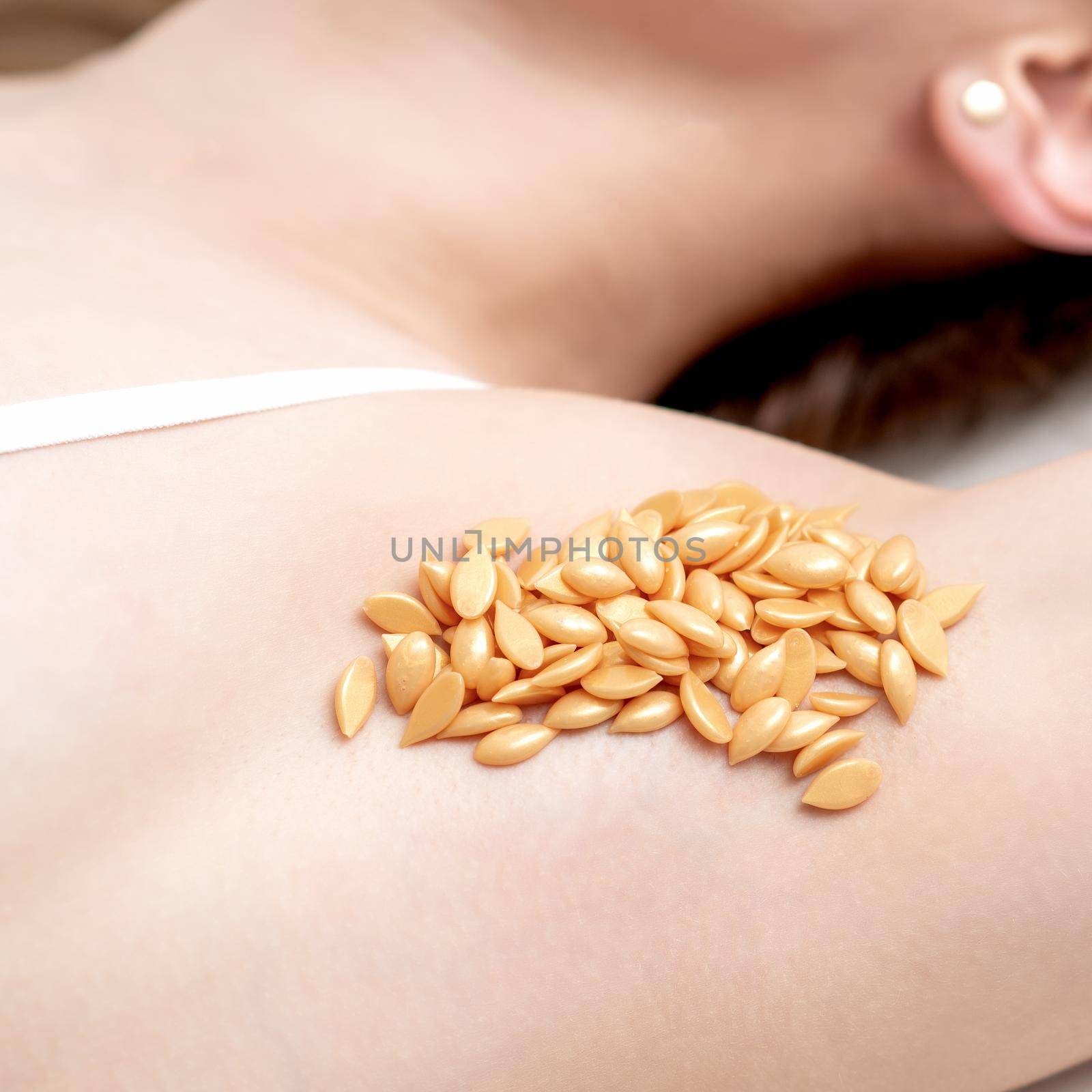 Wax orange beans on armpit of young caucasian woman. Depilation concept