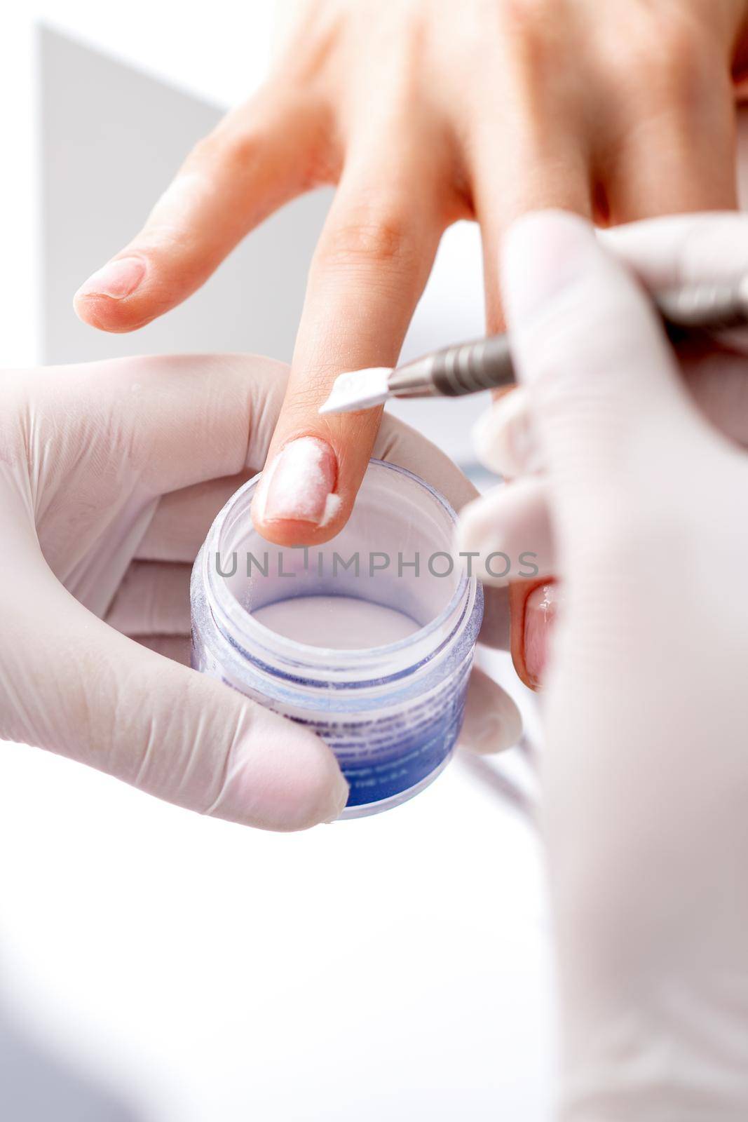 Close up of the process of applying acrylic powder on the nails of a young woman in a beauty salon