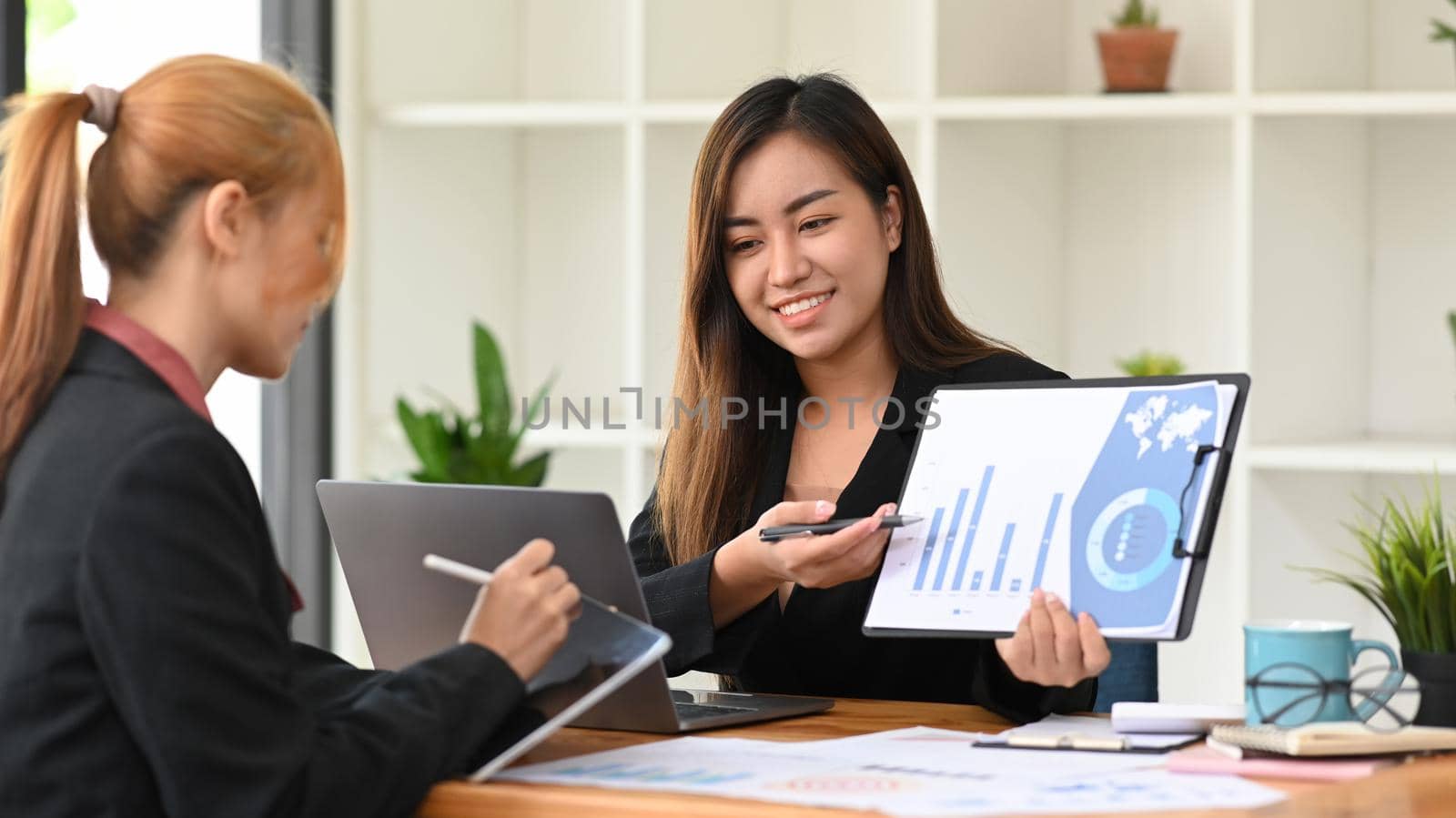 Two young female financial advisor preparing presentation for company clients or investors.