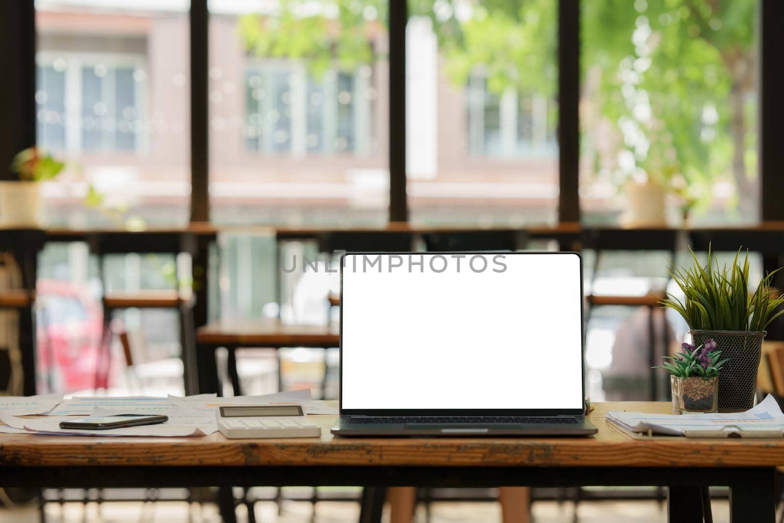 Front view of Mock up laptop computer and office supplies gadget. Blank screen for graphic display montage.