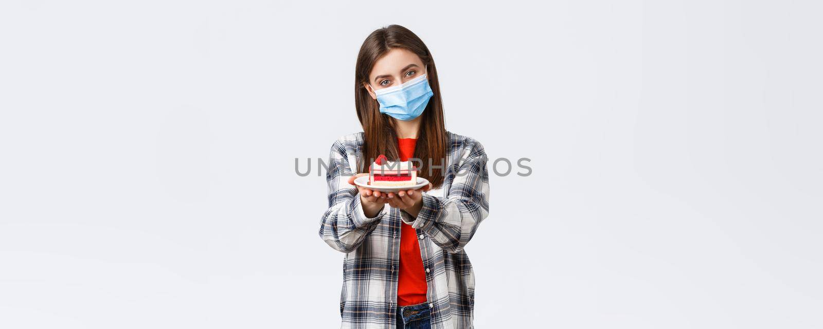 Coronavirus outbreak, lifestyle during social distancing and holidays celebration concept. Tender caring girlfriend made homemade cake, giving it to you, wear medical mask and smiling by Benzoix