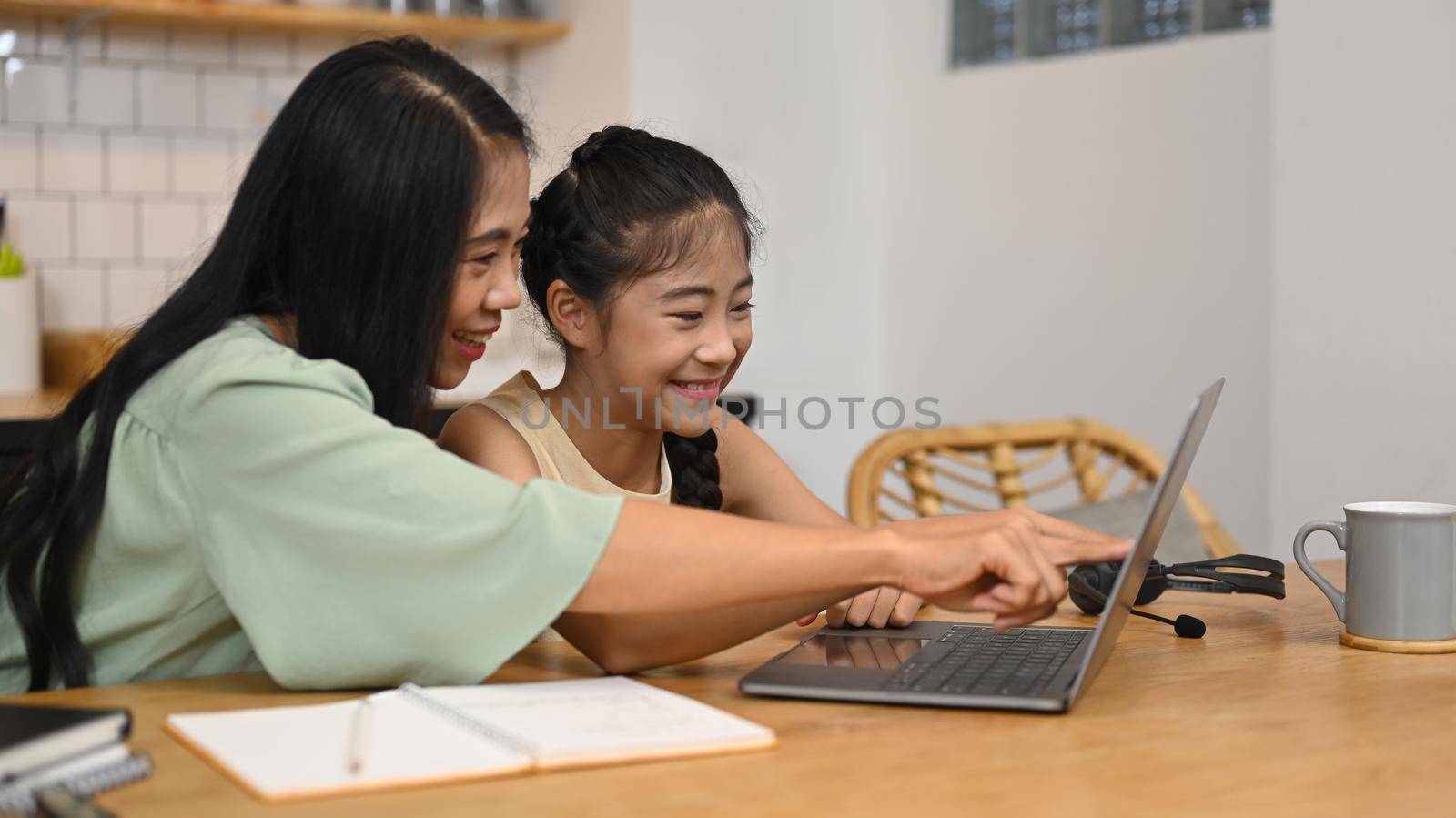 Cute asian girl with mother doing homework at home. Education and school concept.