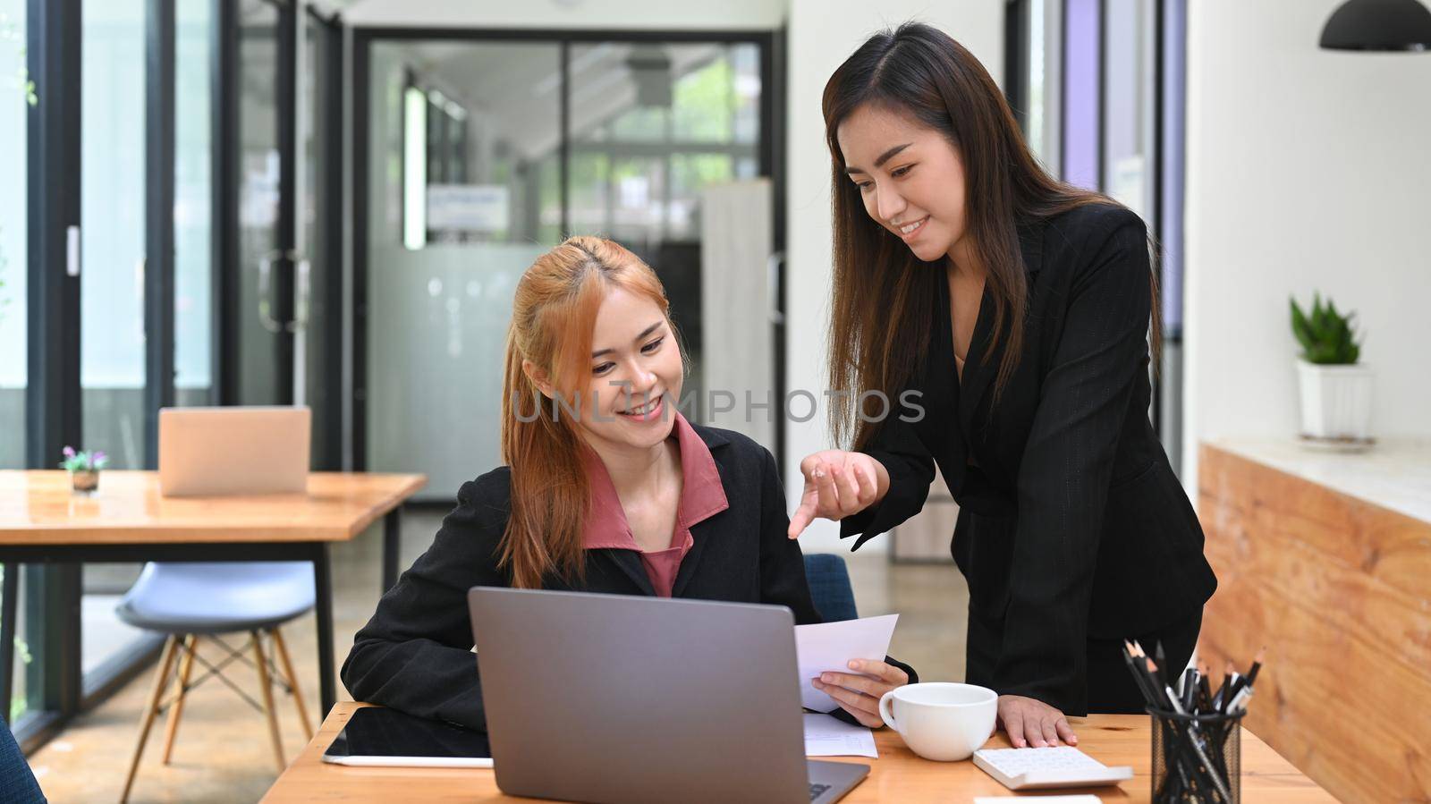 BUsiness colleagues sharing ideas, discussing discussing information online at modern office by prathanchorruangsak