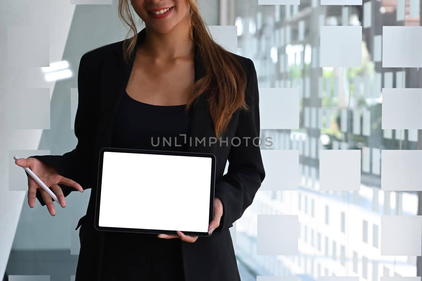 Young businesswoman holding and showing digital tablet with empty display for graphic display montage.
