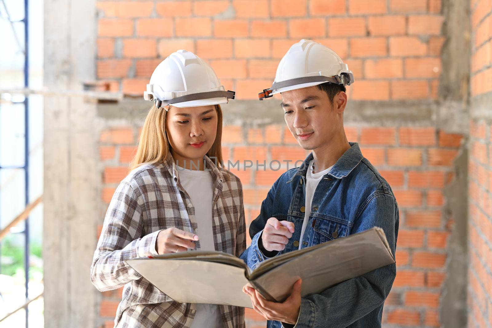 Civil engineer and woman architect working and discussing on plan at construction site by prathanchorruangsak