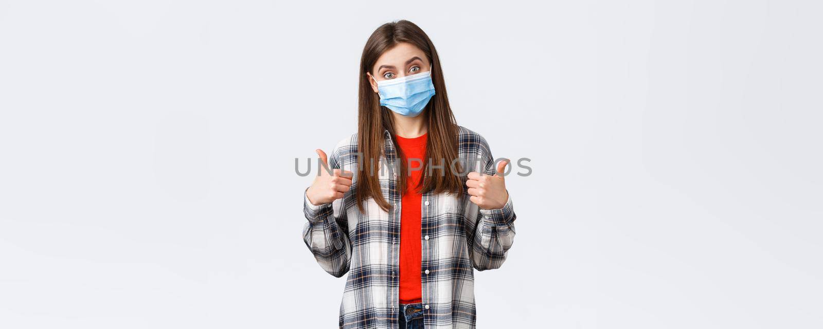 Coronavirus outbreak, leisure on quarantine, social distancing and emotions concept. Very good congratulations. Supportive cute woman in medical mask show thumb-up, like and approve.