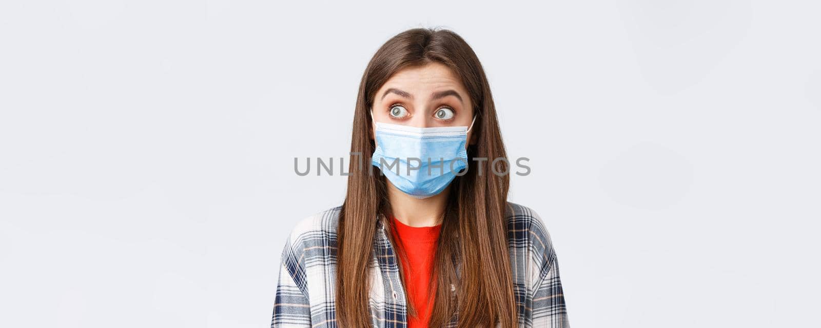 Coronavirus outbreak, leisure on quarantine, social distancing and emotions concept. Close-up of surprised caucasian woman in casual clothes and medical mask, staring left speechless.