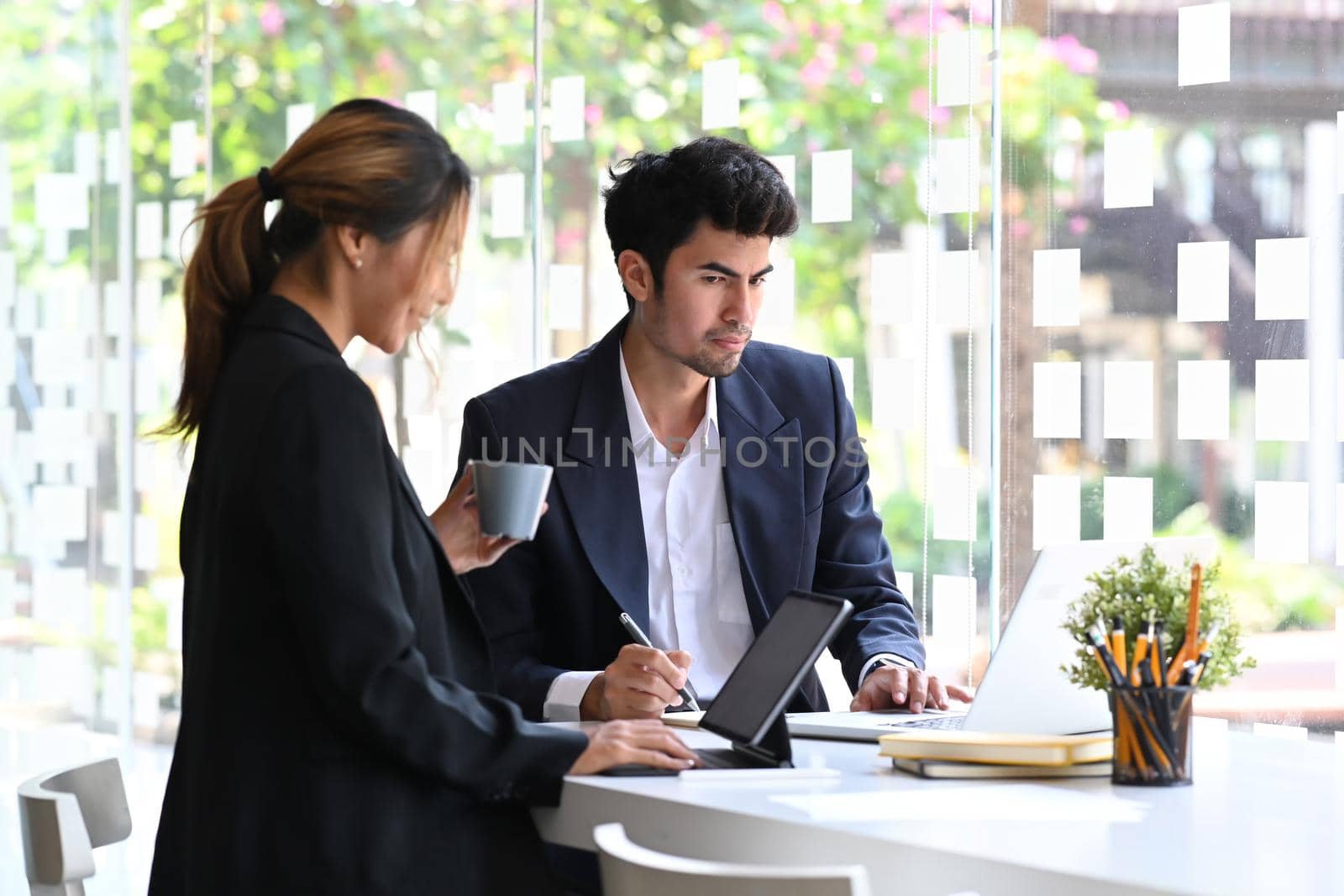 Two successful young entrepreneurs discussing on new project together at bright modern office.