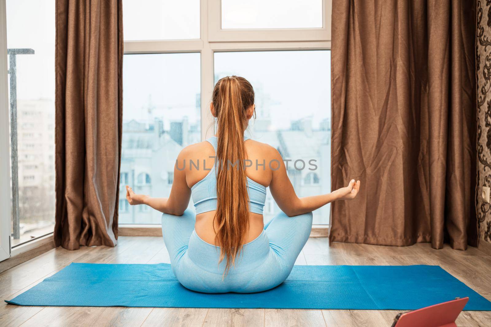 Young woman meditating at home. Girl practicing yoga in class. Relaxation at home, body care, balance, healthy lifestyle, meditation, mindfulness, recreation, workout, fitness, training concept by Matiunina