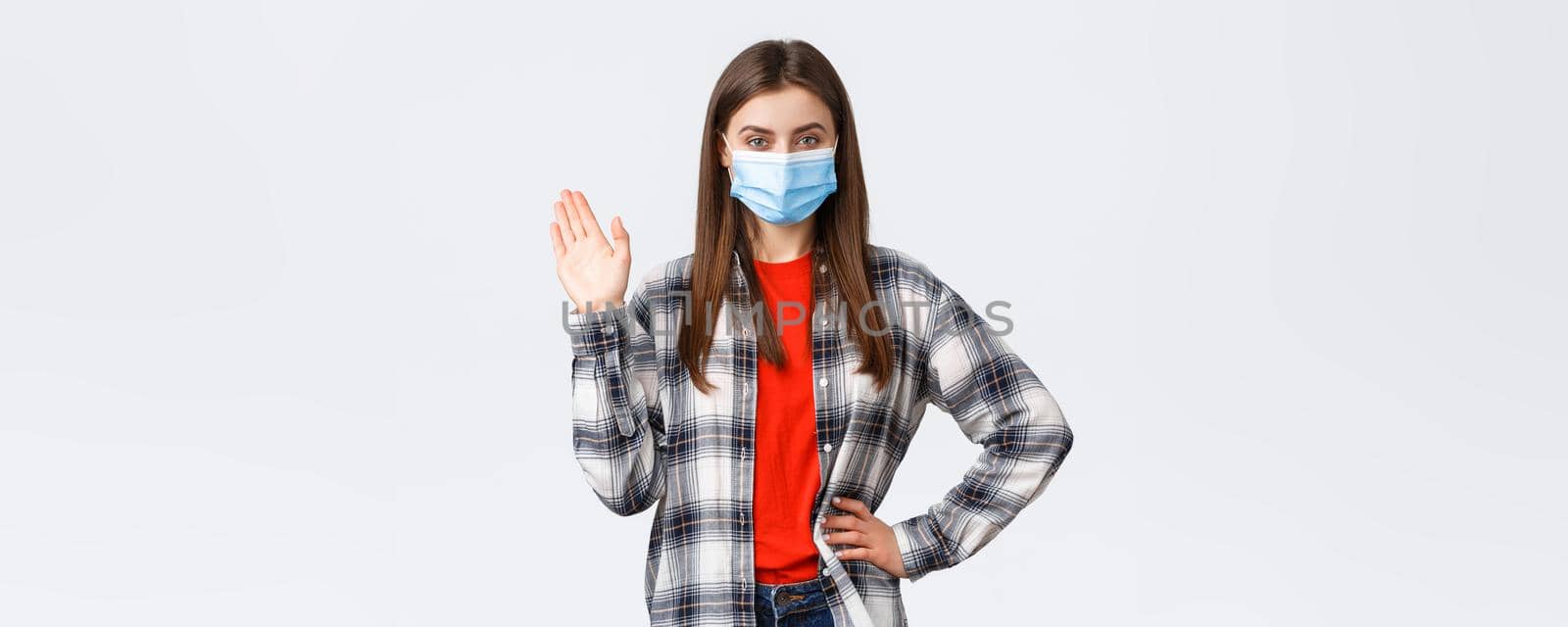 Different emotions, covid-19 pandemic, coronavirus self-quarantine and social distancing concept. Cheerful woman in medical mask, employee working from home, say hi waving hand during video-chat.