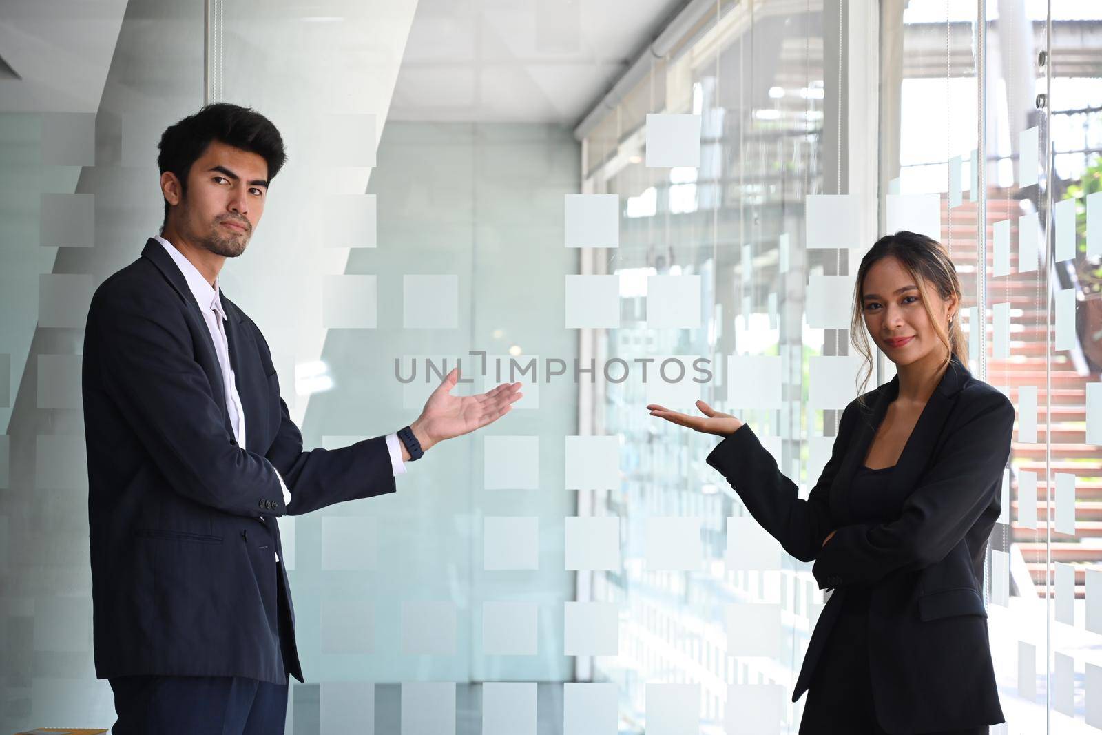 Young businesspeople in formal suit presenting, showing open hand palm with copy space.