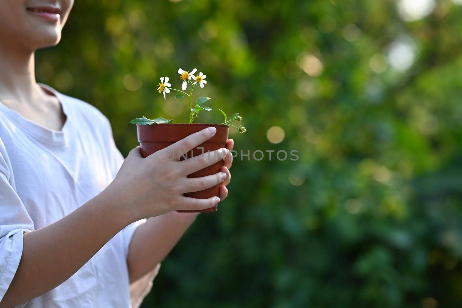 Happy asian girl holding a flower pot in hands. Saving the world, earth day concept. by prathanchorruangsak