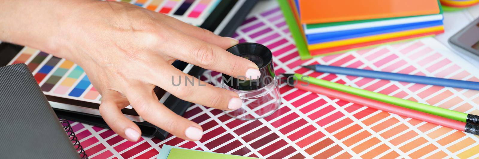 Girl designer looking through magnifying glass at colour palette by kuprevich