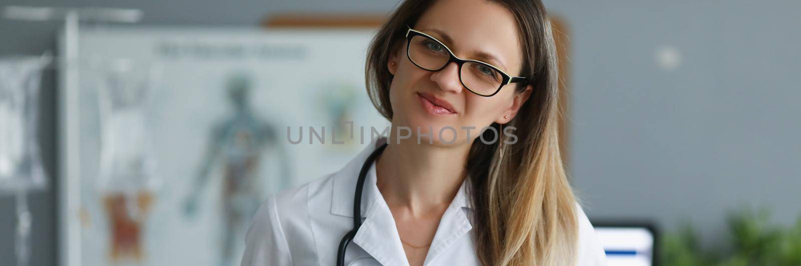 Professional medical worker posing with clipboard in clinic by kuprevich