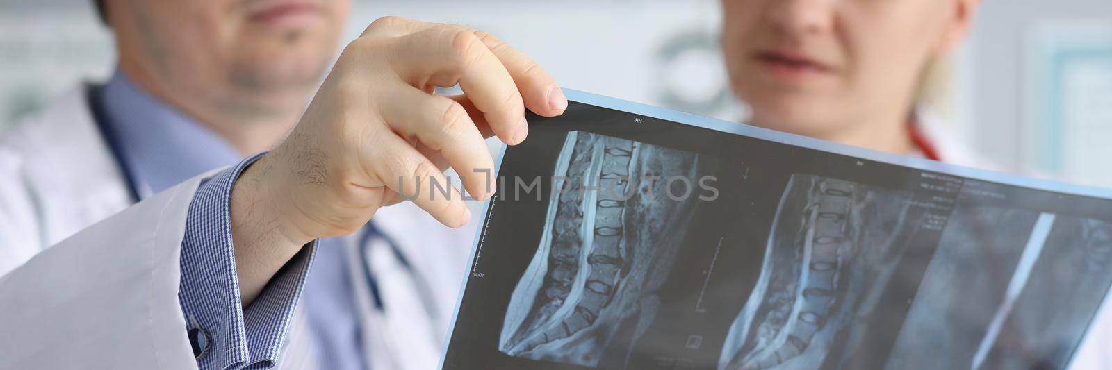 Close-up of doctor discussing patients xray result with colleague in hospital. Medical workers examine back scan. Healthcare, medicine, diagnostic concept