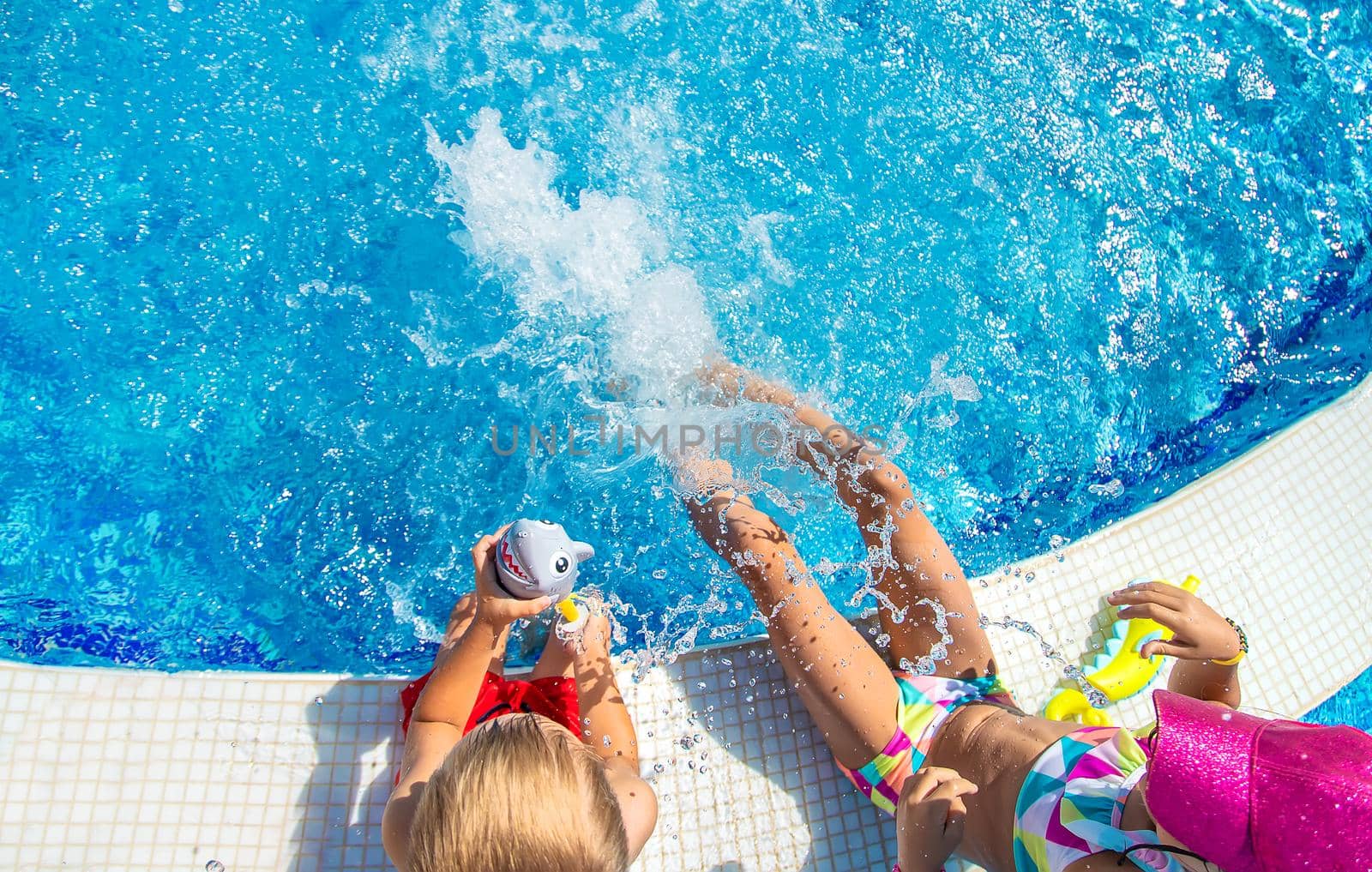 Children splash water with their feet in the pool. Selective focus. Kids.