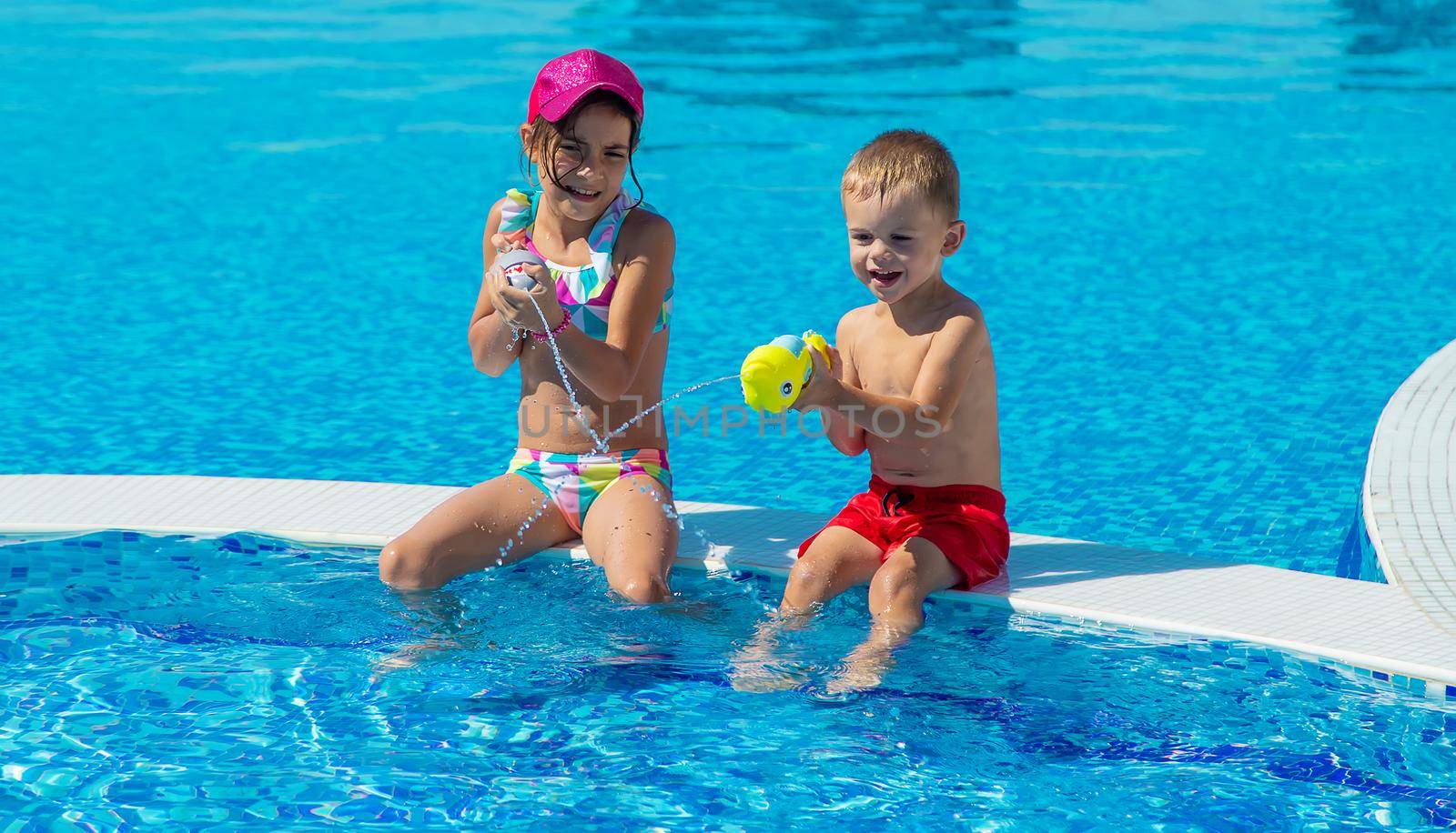 Children play with water pistols in the pool. Selective focus. Kids.
