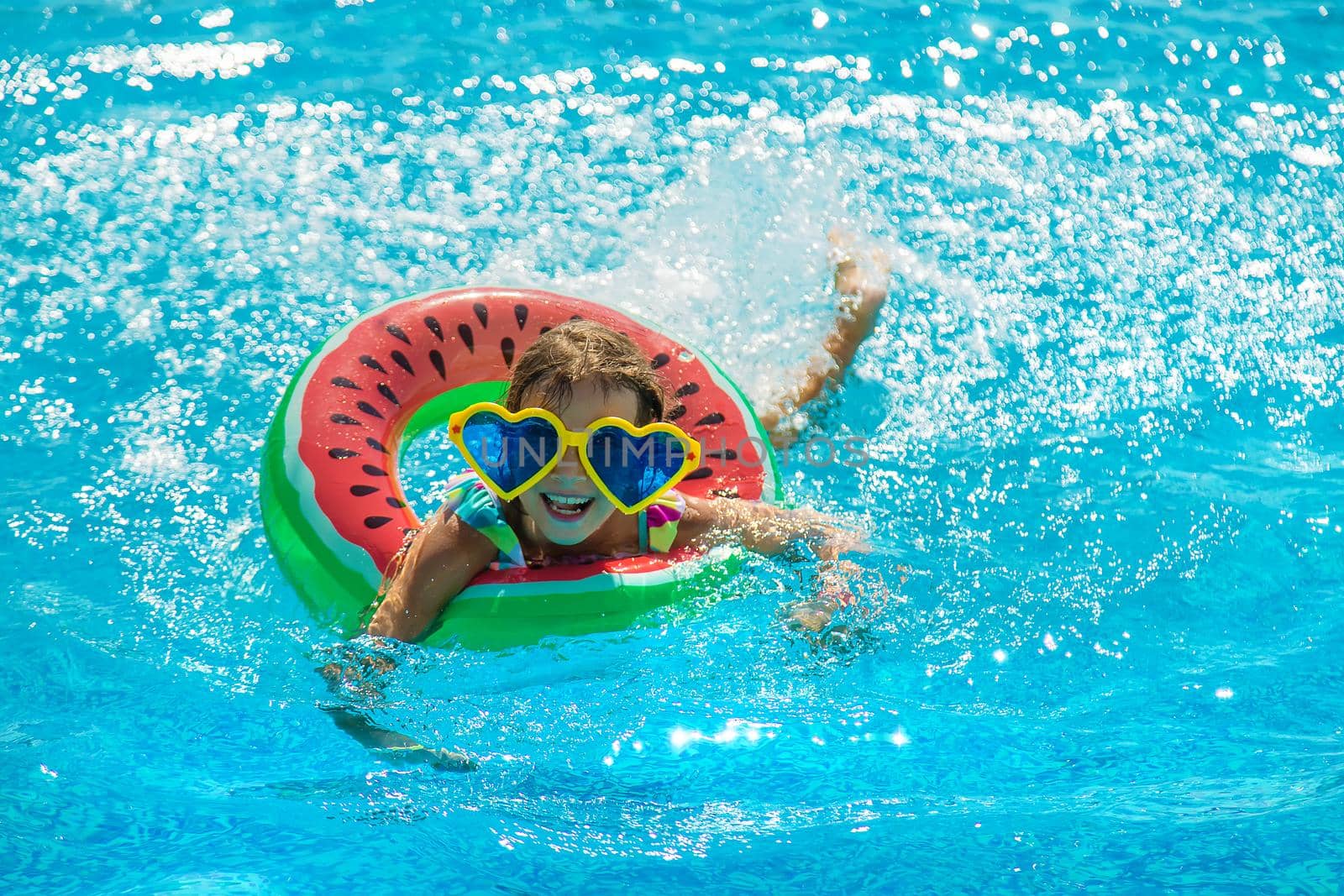 The child in the pool swims in a circle. Selective focus. Kid.