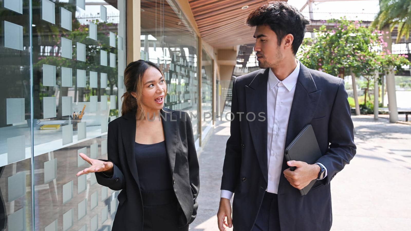 Handsome male business leader and his assistant walking outside office building.