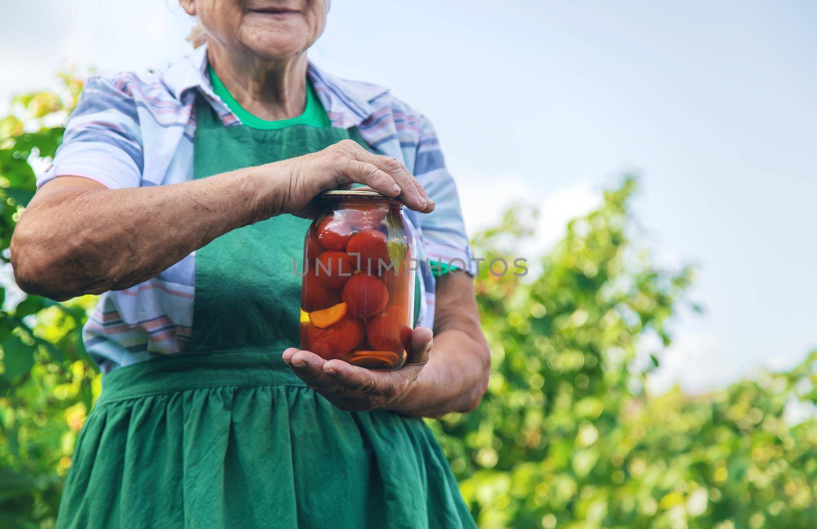 Grandmother canning tomatoes for the winter. Selective focus. Food.