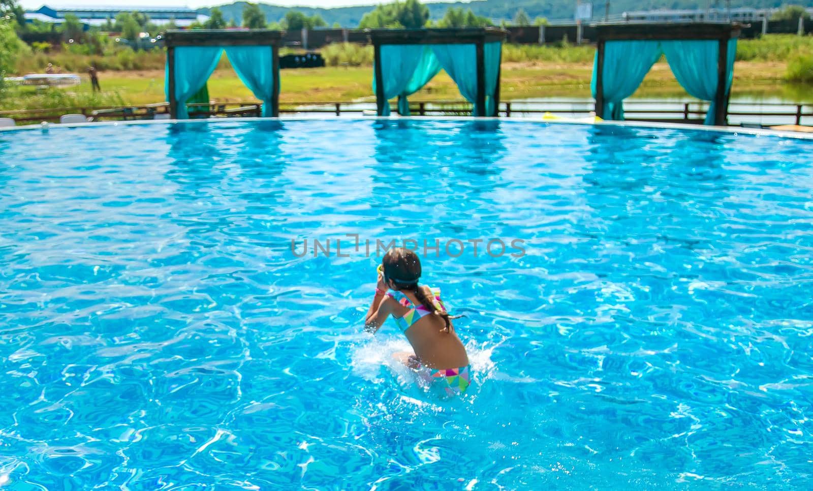 The child jumps dives into the pool. Selective focus. Kid.