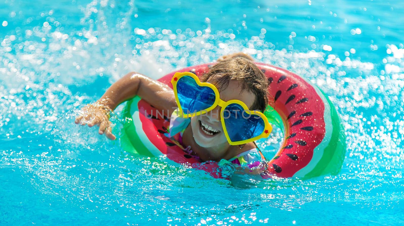 The child in the pool swims in a circle. Selective focus. Kid.