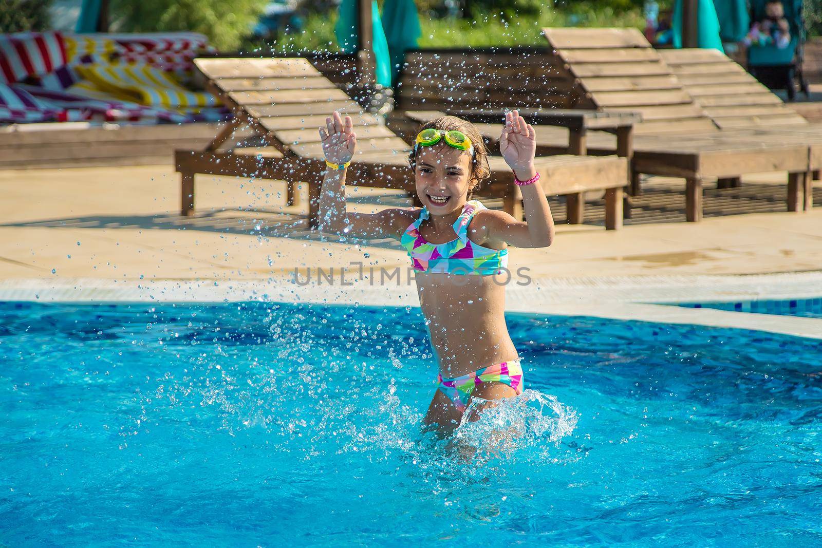 A child in the pool splashes water. Selective focus. Kid.