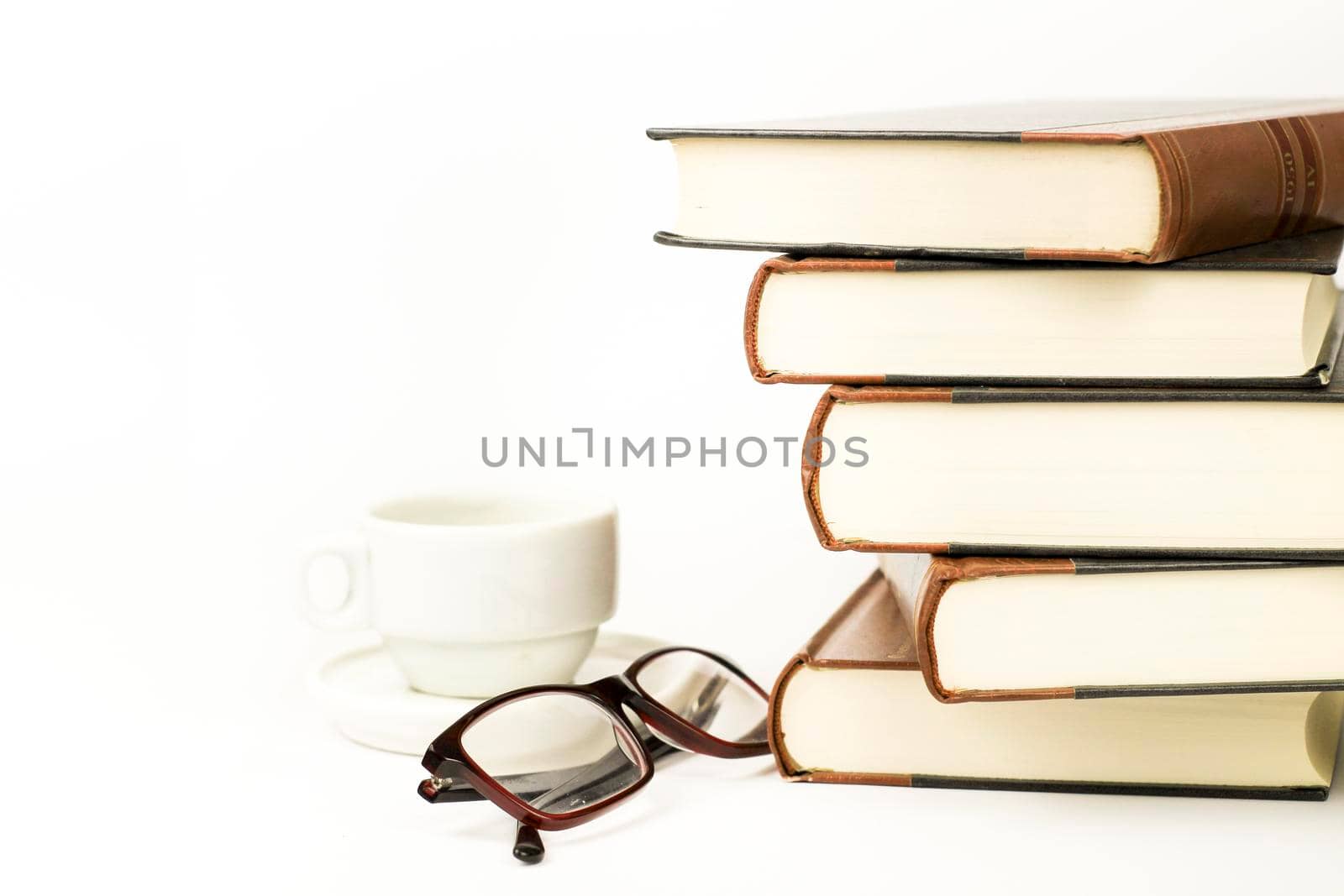 Stacked books next to cup of coffee and eyeglasses by soniabonet