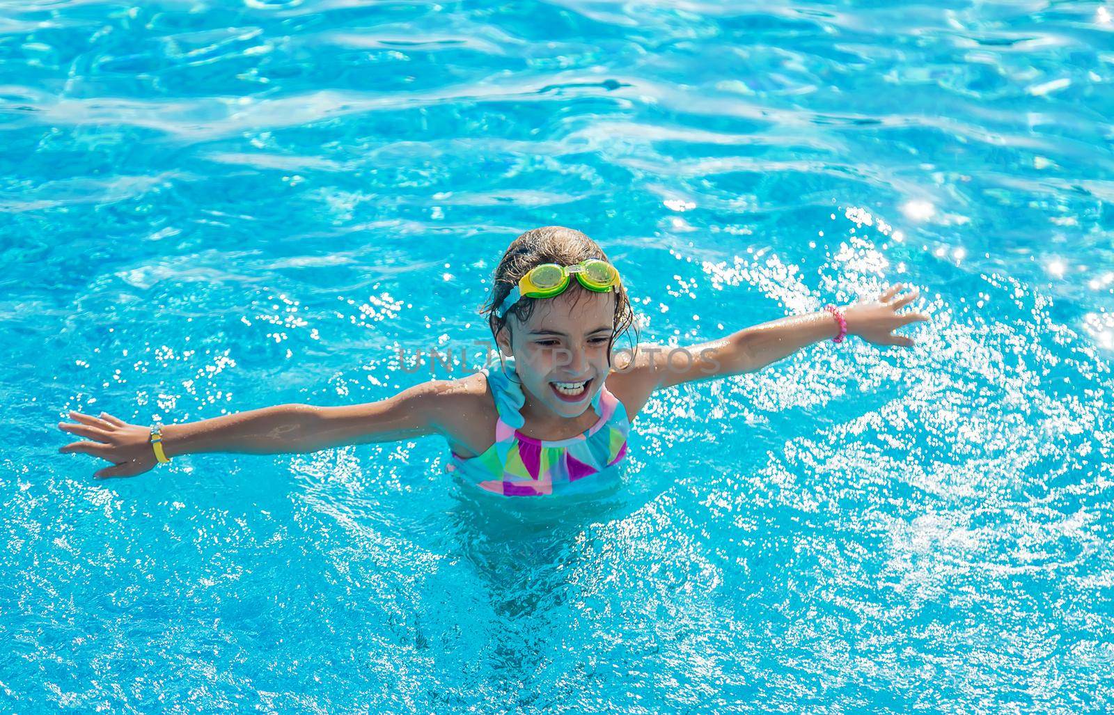 A child in the pool splashes water. Selective focus. Kid.