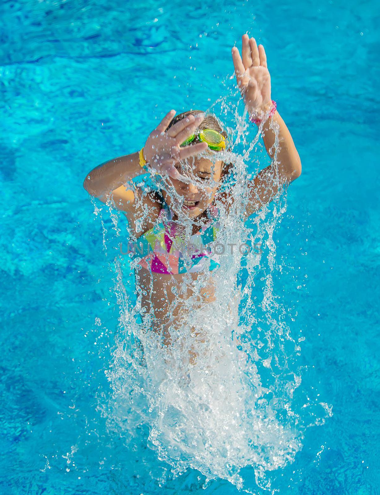 A child in the pool splashes water. Selective focus. Kid.