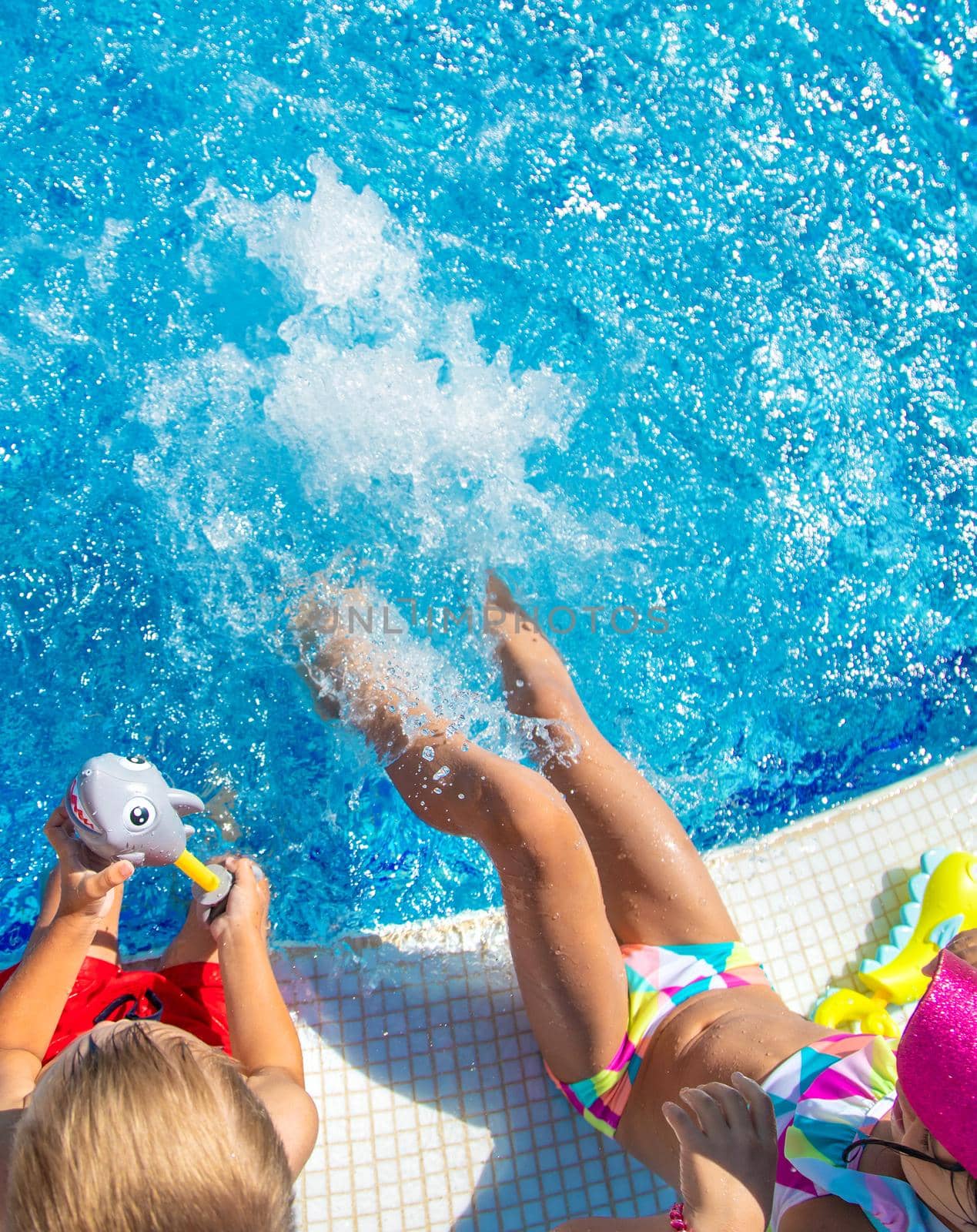 Children splash water with their feet in the pool. Selective focus. Kids.