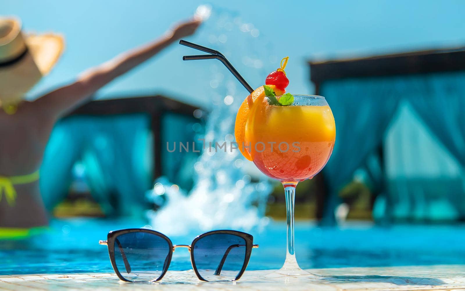 Woman with cocktail near the pool. Selective focus. Drink.