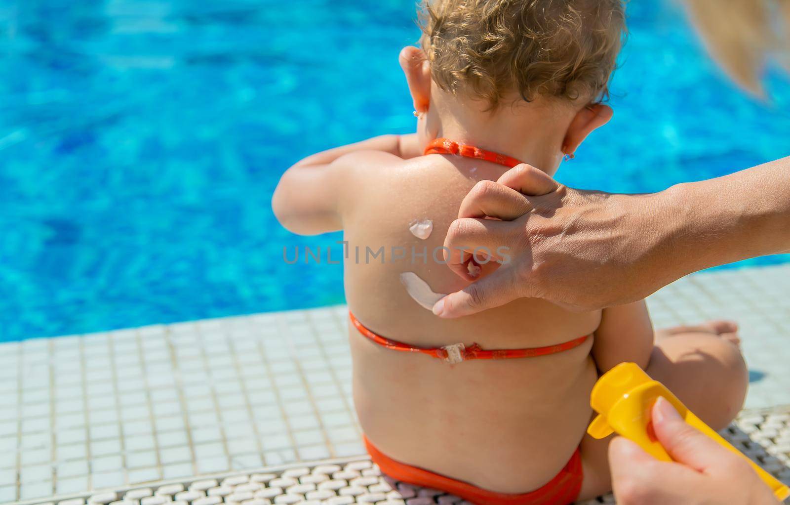 Mother smeared sunscreen on the back of the child. Selective focus. Baby.
