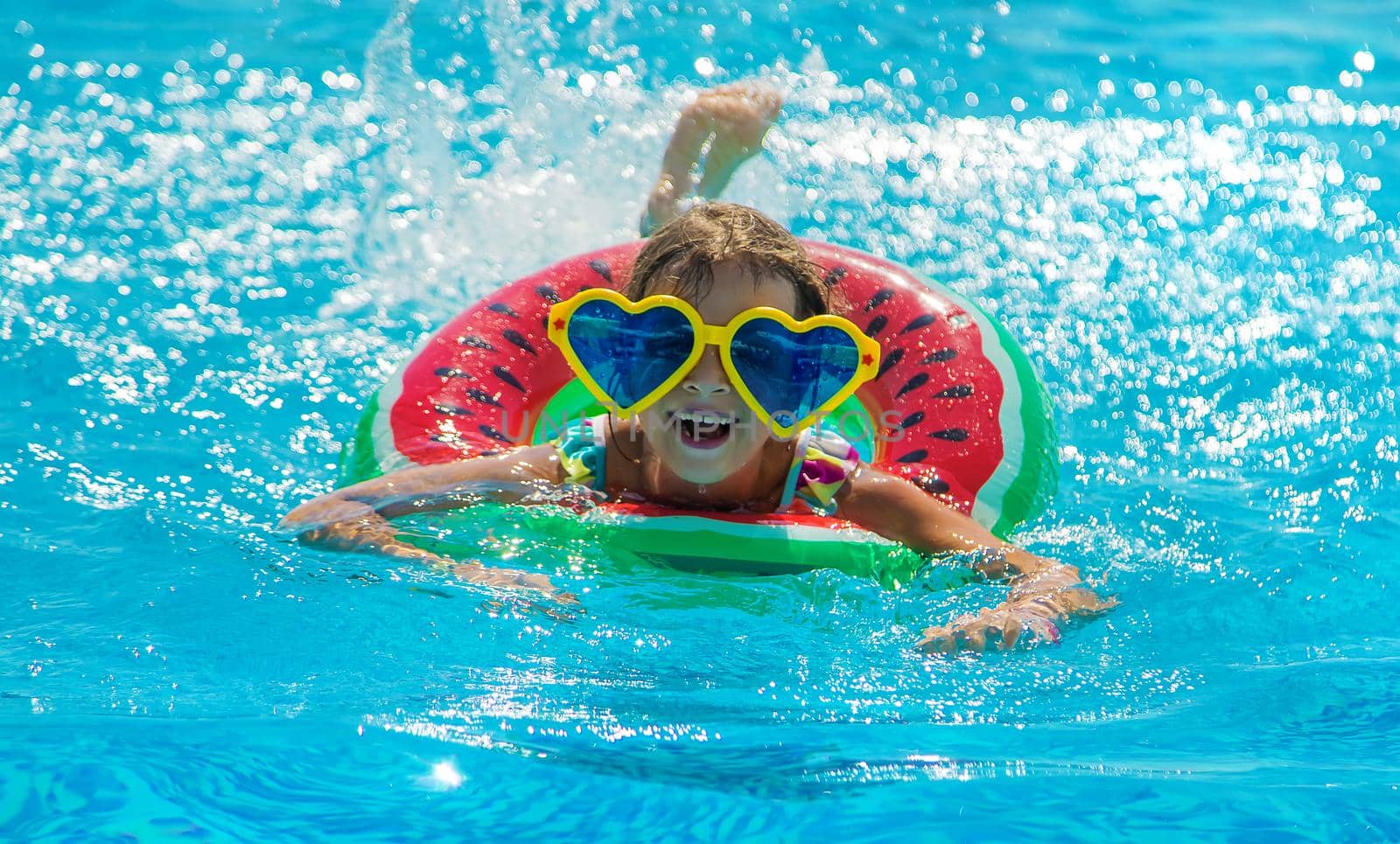 The child in the pool swims in a circle. Selective focus. Kid.