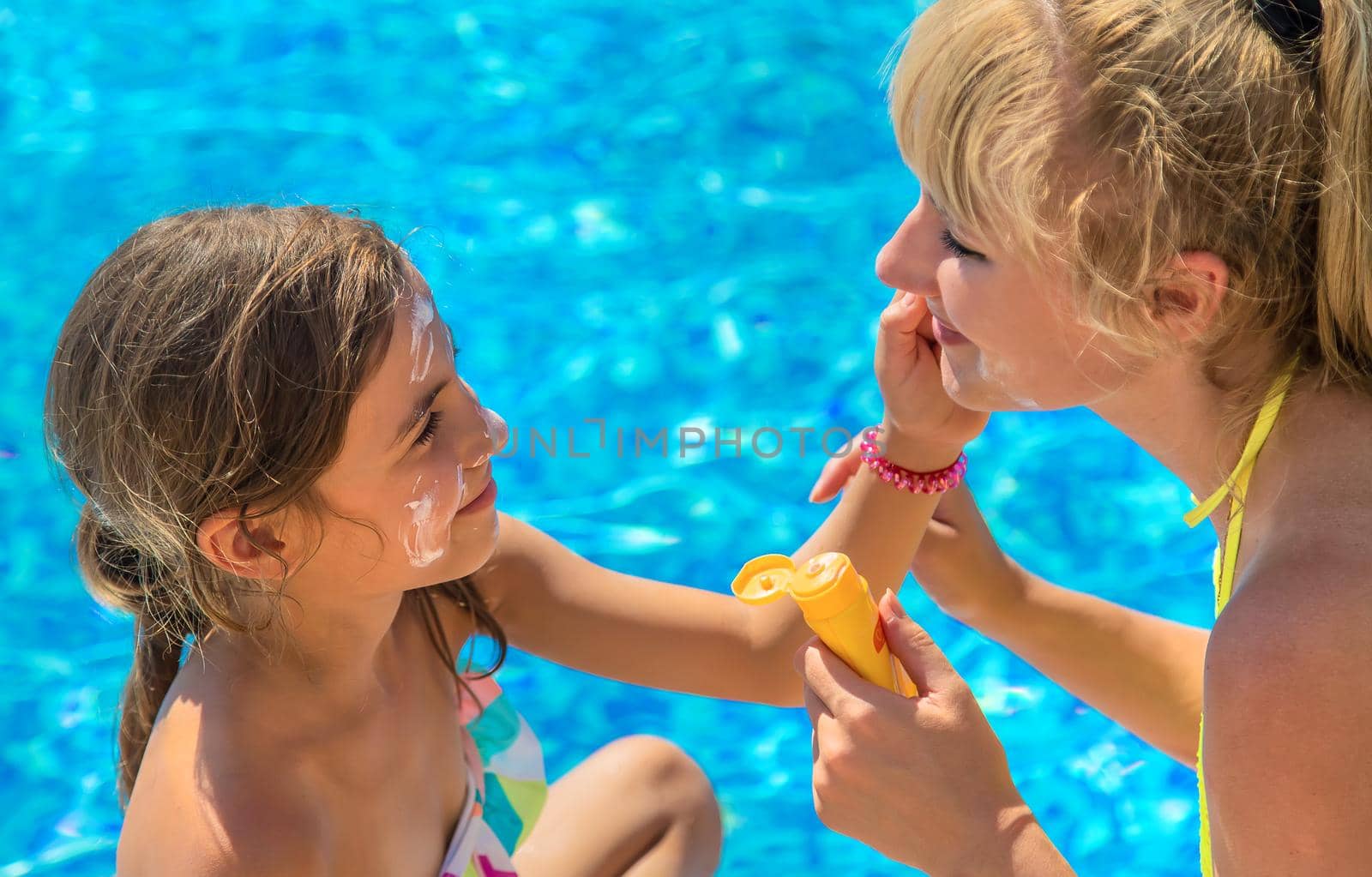 Mother smears sunscreen on the child face. Selective focus. Kid.