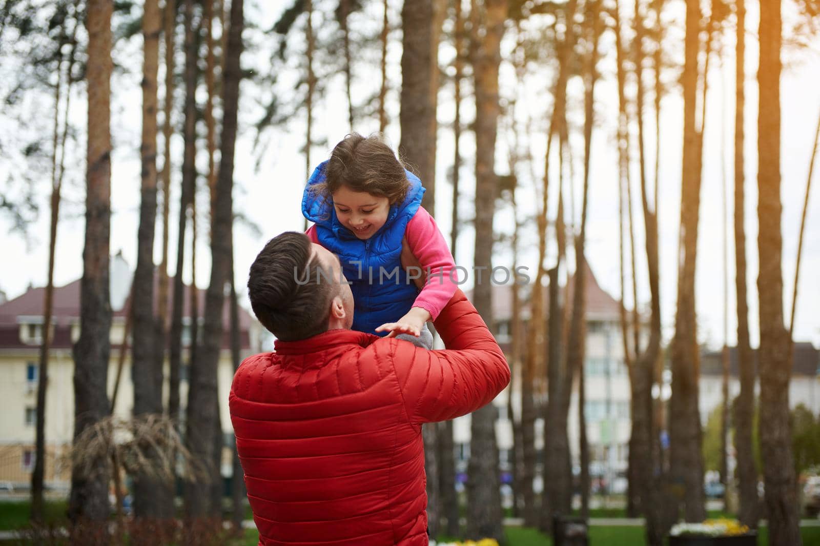 Happy joyful child plays with father outdoors. Loving dad having fun with her daughter throwing her into the air. Father's day, childhood, parenting, fatherhood, family relationships