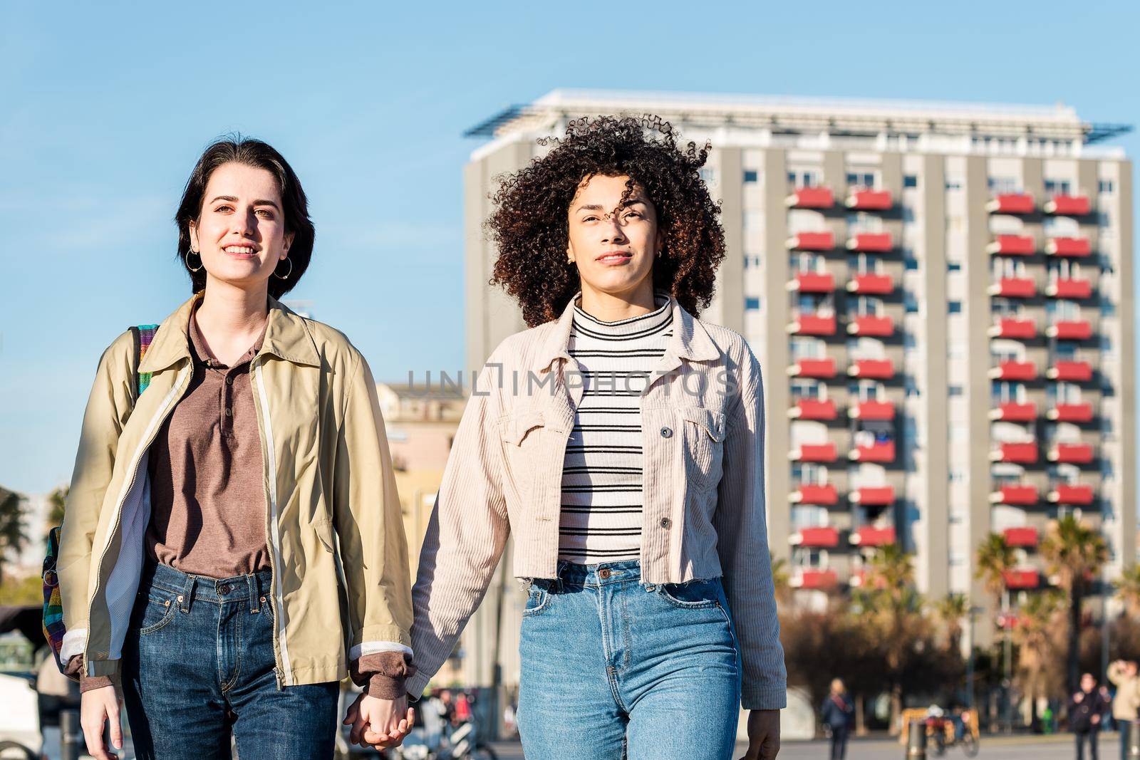 young interracial couple of girls walk around town holding hands, concept of sexual freedom and racial diversity