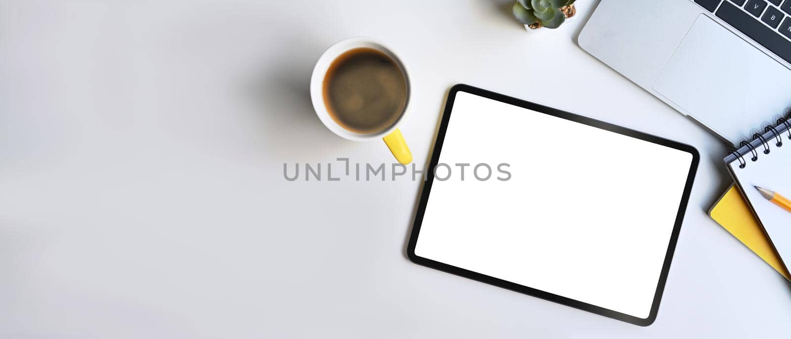 Modern workplace with digital tablet, laptop computer and coffee cup on white table. by prathanchorruangsak