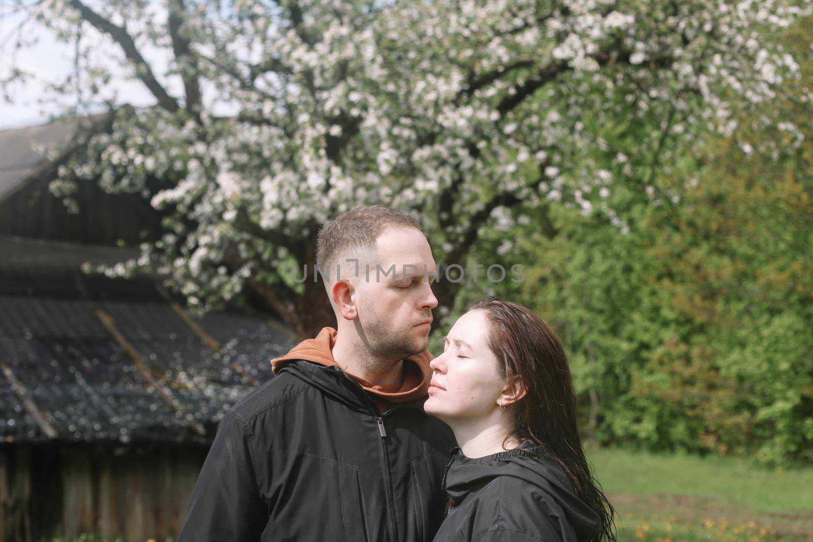 Sensual woman and man in cherry bloom. Couple in love in blossoming garden in spring. Love and romance, relationship, happy family outdoors by paralisart